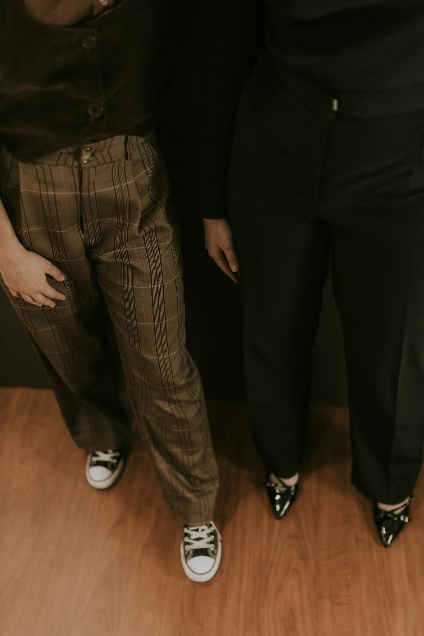 A stylish pair showcasing trendy pants and footwear with a warm indoor ambience.