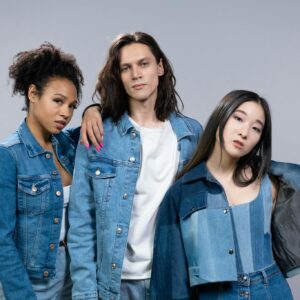 Trendy young adults in denim outfits showcasing diversity and modern style in a studio portrait.